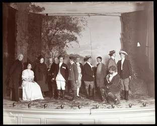 The cast on stage in costume from an amateur production of a play titled 